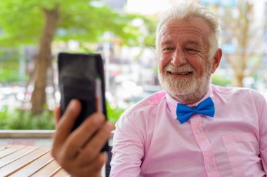 Portrait of handsome senior tourist man wearing stylish clothes while exploring the city of Bangkok, Thailand