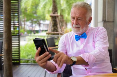 Portrait of handsome senior tourist man wearing stylish clothes while exploring the city of Bangkok, Thailand