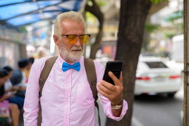Portrait of handsome senior tourist man wearing stylish clothes while exploring the city of Bangkok, Thailand