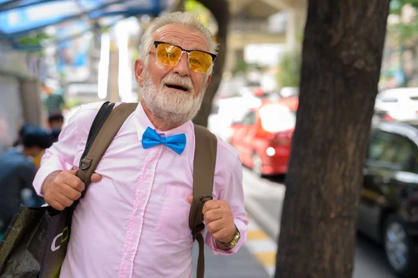 Portrait of handsome senior tourist man wearing stylish clothes while exploring the city of Bangkok, Thailand