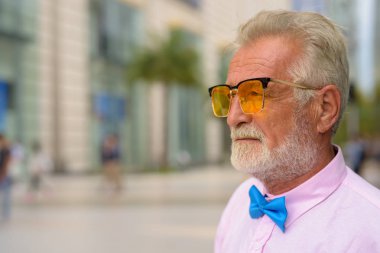 Portrait of handsome senior tourist man wearing stylish clothes while exploring the city of Bangkok, Thailand