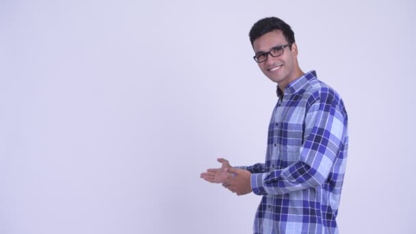 Ευτυχισμένος νεαρός Ινδός χίπστερ που δείχνει κάτι στην πλάτη. — Αρχείο Βίντεο