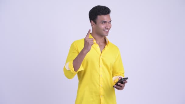 Ευτυχισμένος νεαρός Ινδός επιχειρηματίας που χρησιμοποιεί το τηλέφωνο και φαίνεται έκπληκτος — Αρχείο Βίντεο