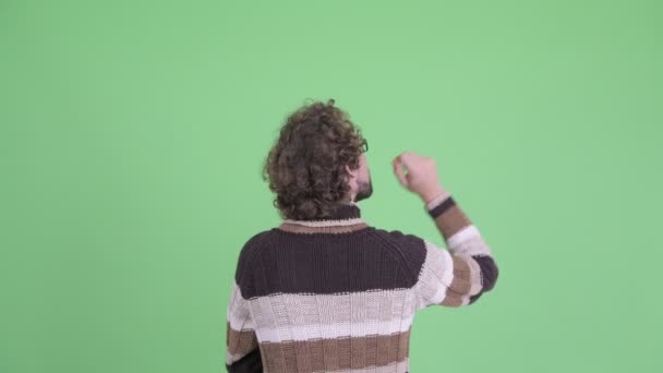 Vue arrière du jeune homme aux cheveux bouclés pensant et pointant du doigt — Video