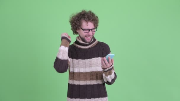 Szczęśliwy młody Brodaty człowiek za pomocą telefonu i uzyskiwanie dobrych wiadomości — Wideo stockowe