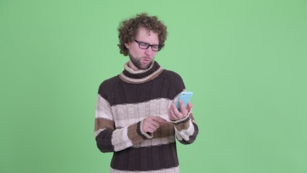 Ευτυχισμένος νέος άνθρωπος με γένια χρησιμοποιώντας το τηλέφωνο και δίνοντας OK πινακίδα — Αρχείο Βίντεο