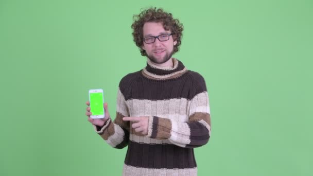 Felice giovane uomo barbuto mostrando il telefono e dando pollici in su — Video Stock