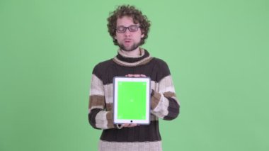 Mutlu genç sakallı adam dijital tablet gösterirken konuşuyor