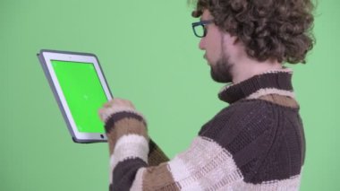 Dijital tablet kullanarak mutlu genç sakallı adamın yakın çekim arka görünümü