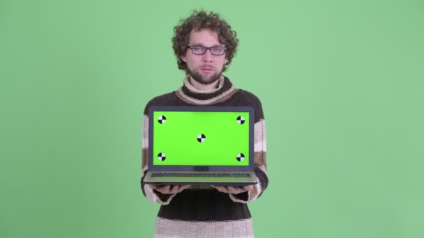 Hombre barbudo joven estresado mostrando el ordenador portátil y recibiendo malas noticias — Vídeos de Stock