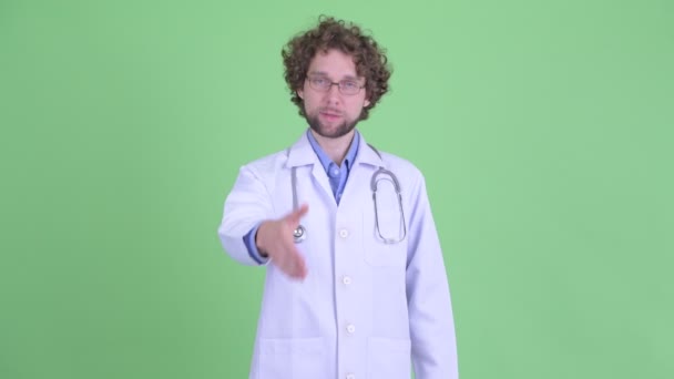 Happy young bearded man doctor giving handshake — Stock Video