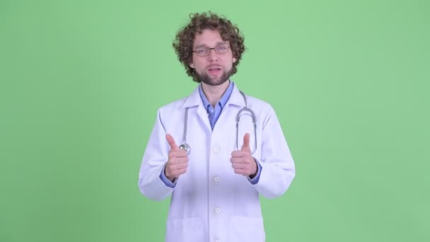 Happy young bearded man doctor giving thumbs up and looking excited — Stock Video