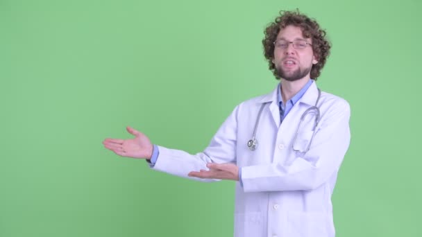 Happy young bearded man doctor showing something and getting good news — Stock Video