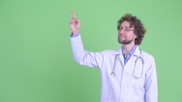 Jovem médico barbudo feliz apontando para cima e recebendo boas notícias — Vídeo de Stock