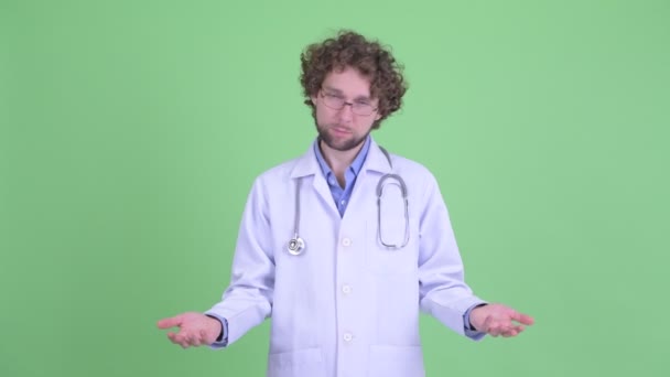 Stressed young bearded man doctor looking sad while shrugging shoulders — Stock Video