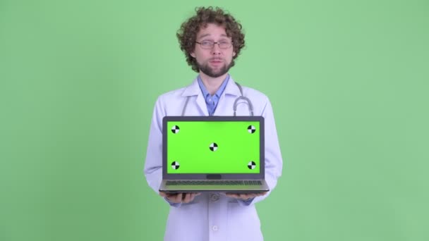 Szczęśliwy młody Brodaty mężczyzna lekarz rozmawia podczas pokazując laptop — Wideo stockowe