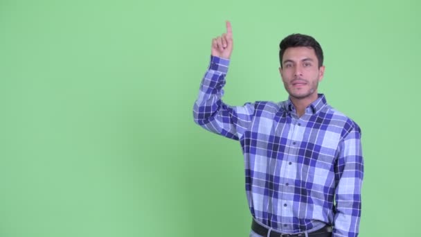 Happy young handsome Hispanic man talking while pointing up — Stock Video