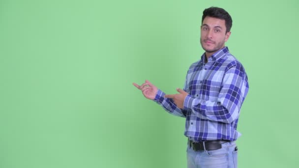 Підкреслив молодий іспаномовних людина представляє щось і давати великі пальці вниз — стокове відео