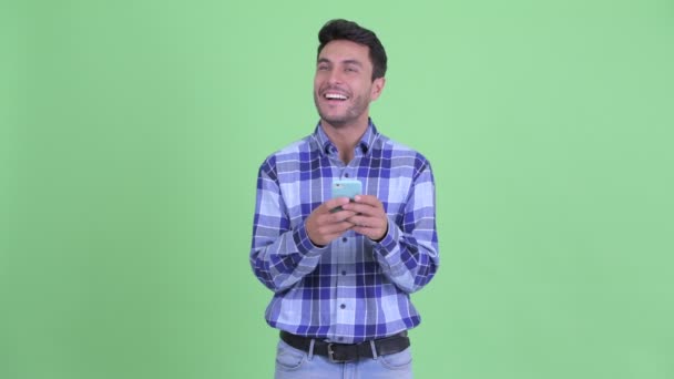 快乐的年轻西班牙裔男子思考，而使用手机 — 图库视频影像