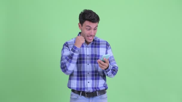 Jovem hispânico feliz usando telefone e recebendo boas notícias — Vídeo de Stock