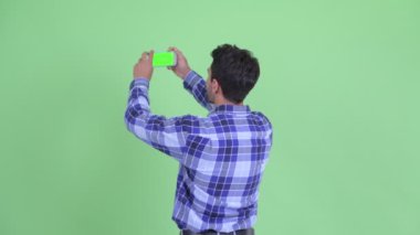 Mutlu genç İspanyol adamın telefonla fotoğraf çektirmesinin arka görünümü