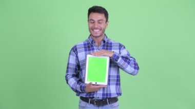Mutlu genç İspanyol adam dijital tablet gösterirken düşünme