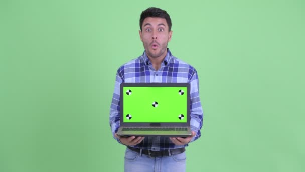 快乐的年轻西班牙裔男子显示笔记本电脑和看起来惊讶 — 图库视频影像