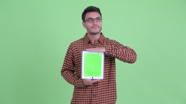 Feliz jovem hispânico hipster homem pensando ao mostrar tablet digital — Vídeo de Stock