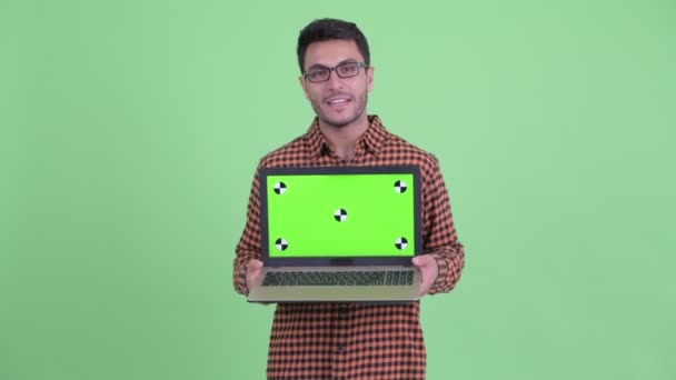 Feliz joven hipster hispano hombre hablando mientras muestra portátil — Vídeos de Stock