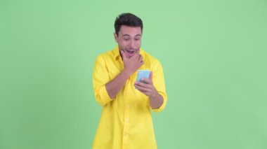 Mutlu genç İspanyol işadamı telefon kullanarak ve şaşırmış görünümlü