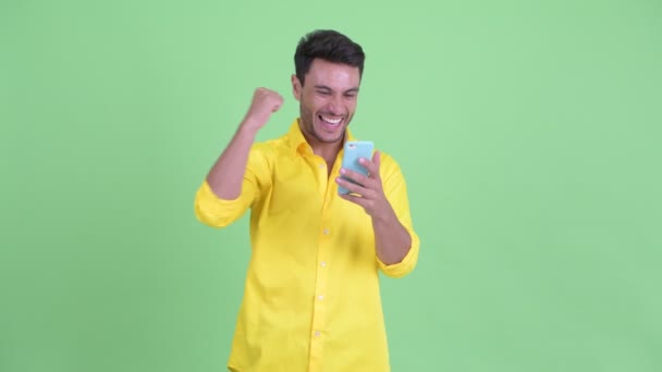 Szczęśliwy młody Hispanic biznesmen za pomocą telefonu i uzyskiwanie dobrych wiadomości — Wideo stockowe