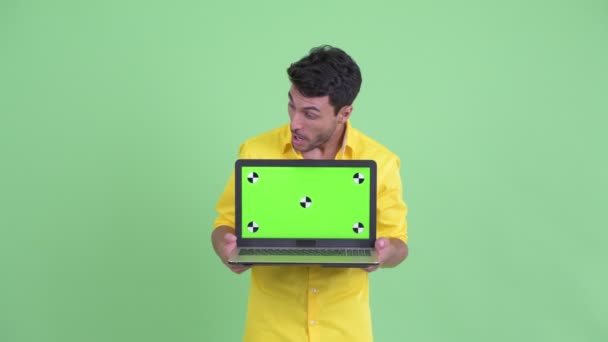 Jovem empresário hispânico feliz mostrando laptop e olhando surpreso — Vídeo de Stock