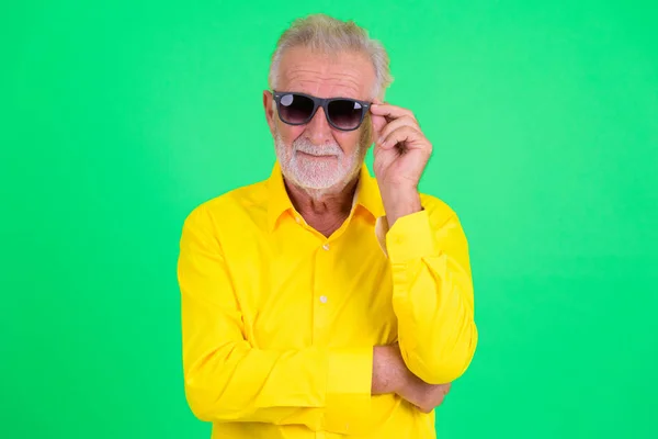 Handsome senior bearded businessman wearing and holding sunglasses — Stock Photo, Image