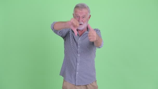 Confused senior bearded man choosing between thumbs up and thumbs down — Stock Video
