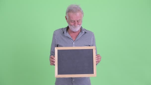 Στρεσαρισμένος γέρος με γένια κρατώντας μαυροπίνακα και να πάρει άσχημα νέα — Αρχείο Βίντεο