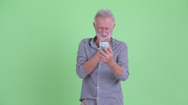 Hombre barbudo mayor estresado usando el teléfono y recibiendo malas noticias — Vídeos de Stock