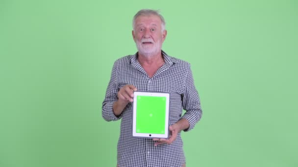Щасливий старший бородатий чоловік думає, показуючи цифровий планшет — стокове відео