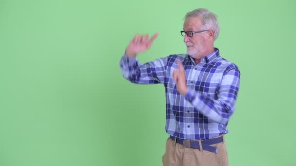 Senior bebaarde hipster man toont iets en geven duimen naar beneden — Stockvideo