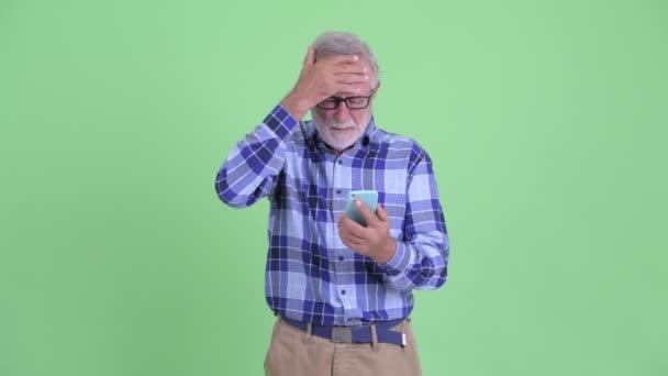 Hombre hipster barbudo mayor estresado usando el teléfono y recibiendo malas noticias — Vídeos de Stock