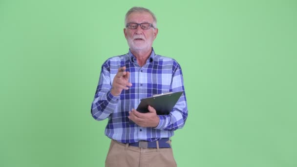 Senior bearded hipster man talking while holding clipboard — Stock Video