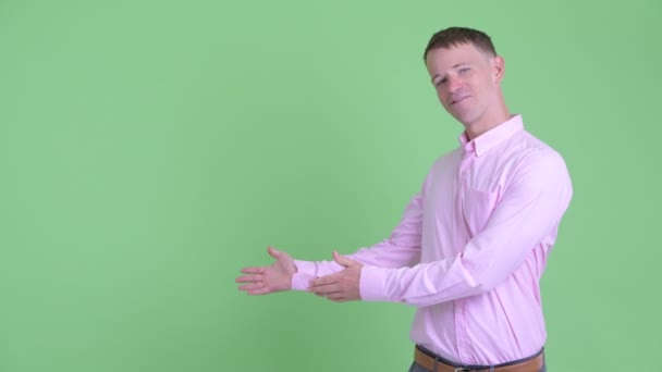 Портрет счастливого бизнесмена, показывающего что-то и показывающего большие пальцы — стоковое видео