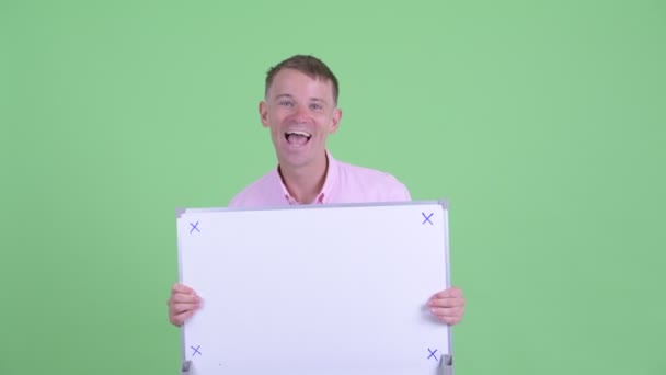 Empresário feliz segurando placa branca e olhando surpreso — Vídeo de Stock