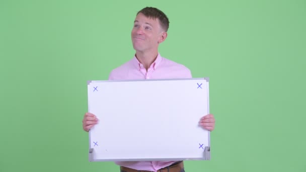 Empresário feliz pensando enquanto segurando placa branca — Vídeo de Stock
