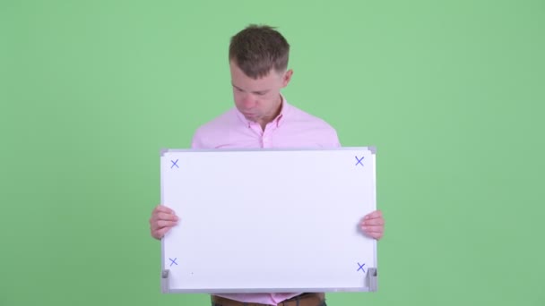 Стрессовый бизнесмен держит белую доску и получает плохие новости — стоковое видео