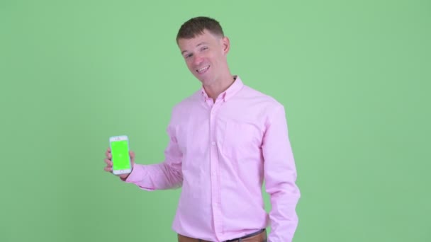 Homme d'affaires heureux montrant le téléphone et donnant pouces vers le haut — Video