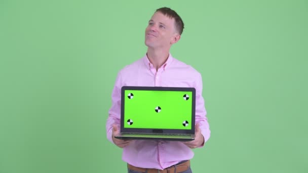 Happy businessman thinking while showing laptop — Stock Video