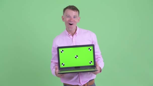 Happy businessman showing laptop and looking surprised — Stock Video