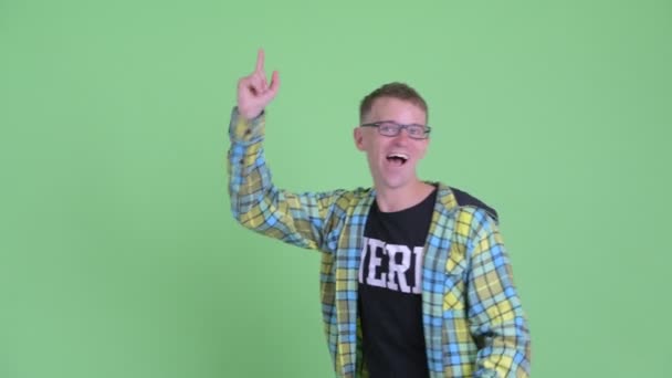 Retrato de hombre nerd feliz apuntando hacia arriba y mirando sorprendido — Vídeo de stock