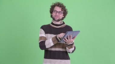 Mutlu genç sakallı adam dijital tablet kullanırken düşünme
