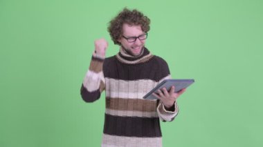 Mutlu genç sakallı adam dijital tablet kullanarak ve iyi haber alıyorum